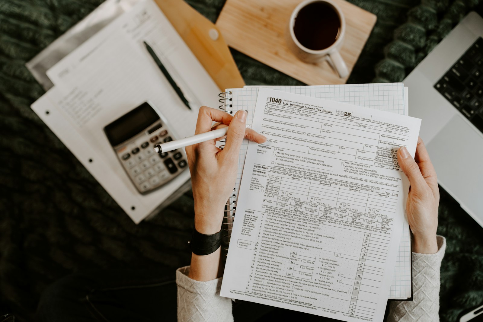 Analyst reviewing compliance documents with calculator and laptop